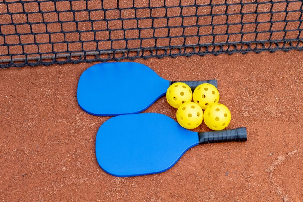 Pickleball paddles and pickleball balls on a court near a net
